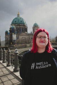 Frau mit roten Haaren und schwarzem T-Shirt steht vor dem Berliner Dom.